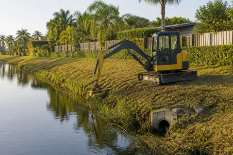 Excavator-mounted mower selectively clearing vegetation from the top of a Central Broward drainage canal bank