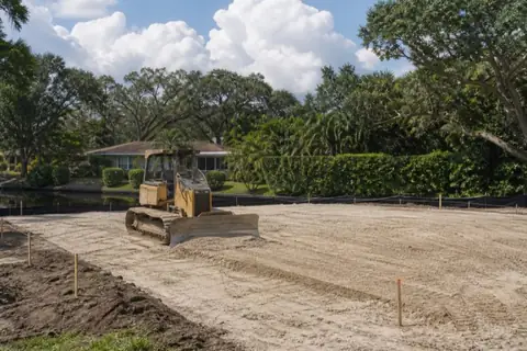 Compact dozer shaping pale sandy fill on a Plantation infill site with canal-side sediment protection