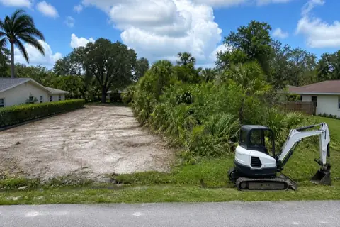Survey-staked Plantation infill lot being selectively cleared between established ranch homes